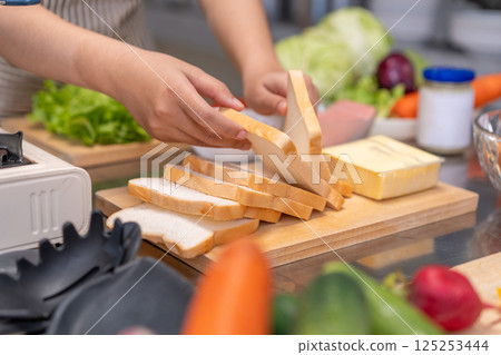 Close-up hands of a Young Female Chef Preparing a Sandwich in a Professional Kitchen Close-up hands of a Young Female Chef Preparing a Sandwich in a Professional Kitchen 125253444