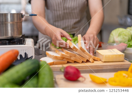 Close-up hands of a Young Female Chef Preparing a Sandwich in a Professional Kitchen Close-up hands of a Young Female Chef Preparing a Sandwich in a Professional Kitchen 125253446