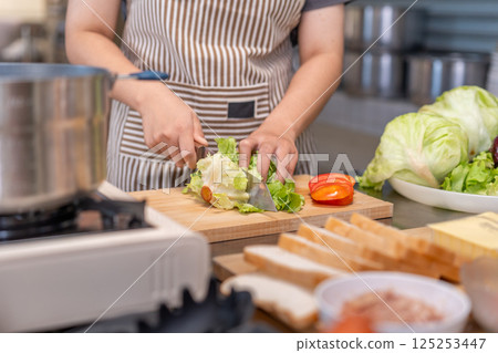 Chef Cutting a head of lettuce on Wooden Cutting Board in Professional Kitchen Chef Cutting a head of lettuce on Wooden Cutting Board in Professional Kitchen 125253447