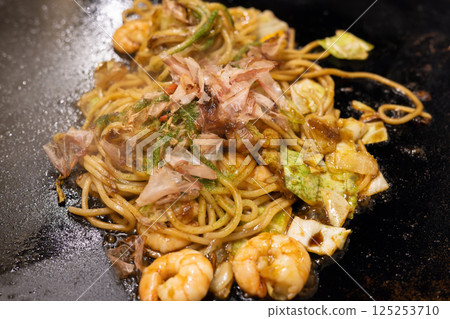 Delicious fried noodles with shrimp sauce served on a hot plate Delicious fried noodles with shrimp sauce served on a hot plate 125253710