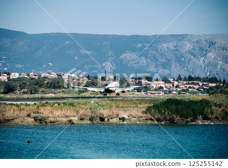 A large jet is taking off from a runway near a body of water 125255142
