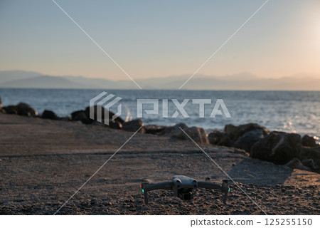 A drone is sitting on the beach near the water 125255150