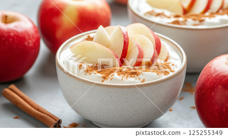 Creamy yogurt topped with apple slices and cinnamon 125255349