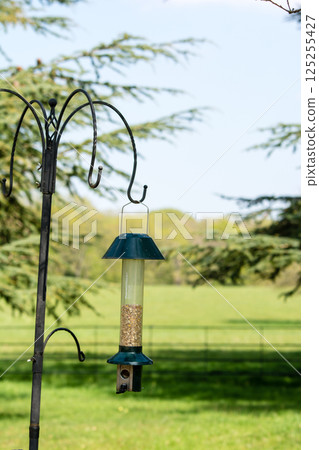 A bird feeder surrounded by a spacious field and trees in Hatchlands, a suburb of London A bird feeder surrounded by a spacious field and trees in Hatchlands, a suburb of London 125255427