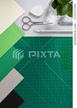 Paper crafting supplies: scissors, craft knife, pencil, tweezers, eraser, paper on gray background. Place for your text. 125255595