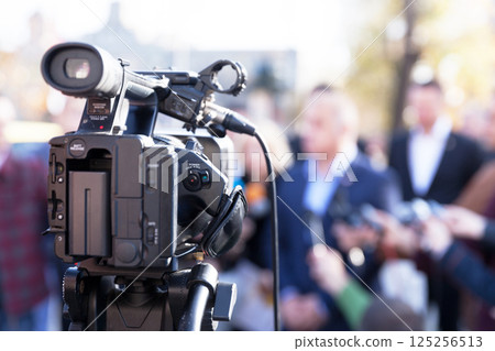 Filming news conference with television camera Filming news conference with television camera 125256513