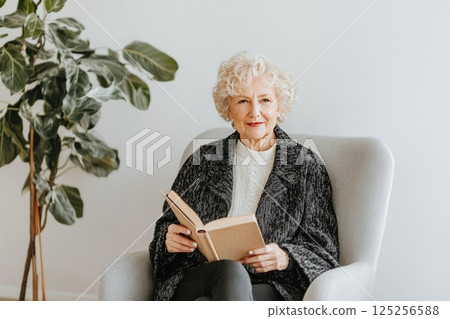 Elderly woman enjoys reading in a modern, minimalist home interior with natural light Elderly woman enjoys reading in a modern, minimalist home interior with natural light 125256588