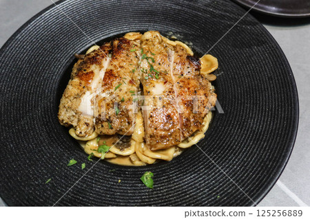 close up of grilled chicken fillet with Orecchiette pasta mixed with a creamy sauce, mushroom and fresh herbs 125256889