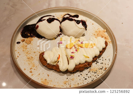 close up of dessert plate, including vanilla ice cream drizzled with a berry sauce, mochi and Croffle topped with whipped cream 125256892