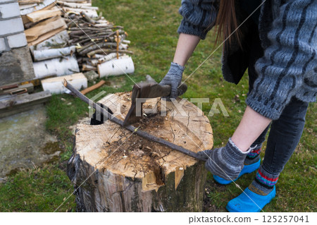 Cutting branches on the deck. A girl cuts a branch with an axe Cutting branches on the deck. A girl cuts a branch with an axe 125257041