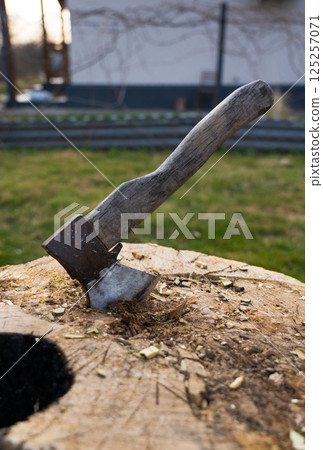 Axe is hammered into an oak block. The axe is stuck in the deck 125257071