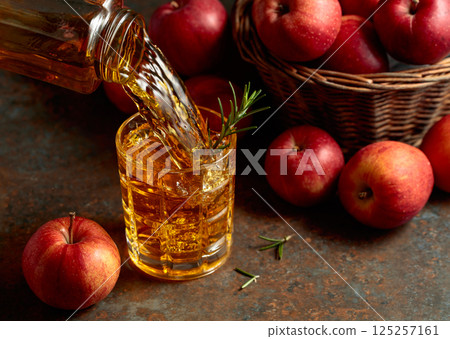 Apple juice is poured from a bottle into a glass. Apple juice is poured from a bottle into a glass. 125257161