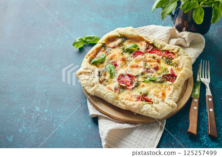 Galette-type pie made from puff pastry and filled with tomatoes, mozzarella cheese and pesto sauce. Galette Caprese 125257499