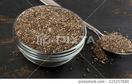 Clear glass bowl filled with dry chia seeds, top view 125257880