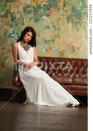 Perfect healthy woman wearing fashionable dress on green painted background indoor 125257934