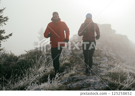 Trail running couple man and woman running on a mountain path 125258652