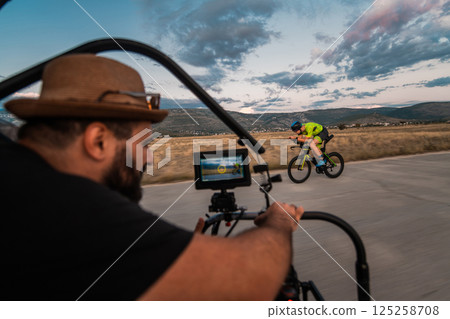 A videographer recording a triathlete riding his bike preparing for an upcoming marathon.Athlete's physical endurance and the dedication required to succeed in the sport. 125258708