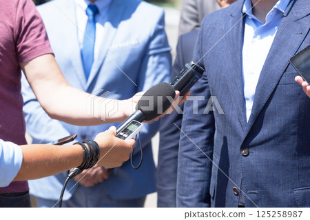 Group of journalists recording speech of business person or politician during press conference 125258987