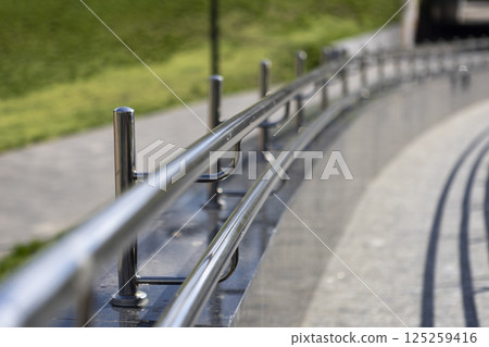 Long row of polished stainless steel railings, ramp for going up or down 125259416