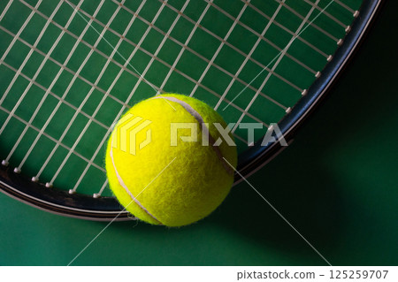Tennis racket and balls on dark green background. Soft sidelight 125259707