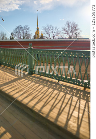 View on the Peter and Paul Fortress spire through iron railings at sunset View on the Peter and Paul Fortress spire through iron railings at sunset 125259772