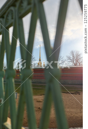 View on the Peter and Paul Fortress spire through iron railings at sunset View on the Peter and Paul Fortress spire through iron railings at sunset 125259775