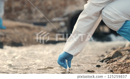 Ecologist sampling water from the river with test tube, Biologist wear protective suit and mask collects sample of waste water from industrial, problem environment, scientist environmentalist Ecologist sampling water from the river with test tube, Biologist wear protective suit and mask collects sample of waste water from industrial, problem environment, scientist environmentalist 125259837