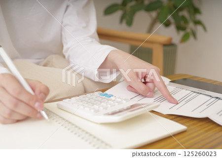 Woman doing calculations on a calculator Woman doing calculations on a calculator 125260023