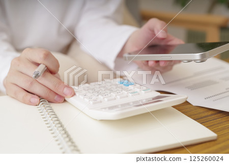 Woman doing calculations on a calculator Woman doing calculations on a calculator 125260024