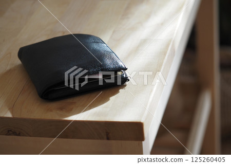 Wallet resting on a wooden table in warm natural light, lost wallet concept Wallet resting on a wooden table in warm natural light, lost wallet concept 125260405