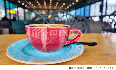 Colorful coffee cup on a table in a lively cafe setting 125260434