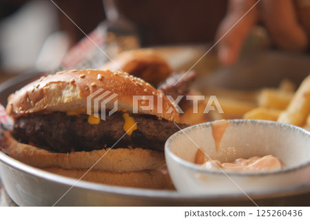 Delicious cheeseburger with fries and sauce during casual dining 125260436
