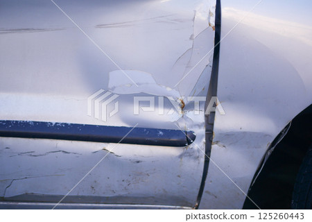 Car damage with visible scratches and dents on the door panel 125260443