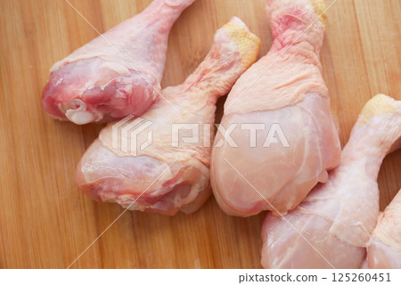 Fresh chicken drumsticks arranged on a wooden cutting board Fresh chicken drumsticks arranged on a wooden cutting board 125260451