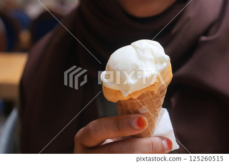 Enjoying a delicious ice cream cone in a cozy cafe setting 125260515