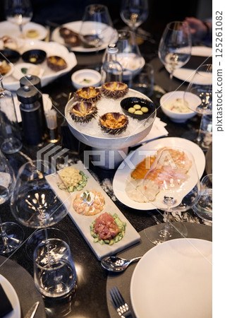 Champagne tasting, Wine glasses are on the table, stylish table setting, wine is poured from a bottle and decanter, sparkling wine bubbles, snacks, people smell the aroma and taste the wine 125261082