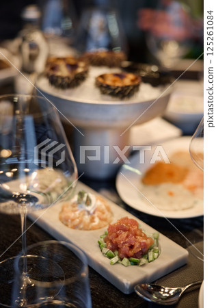 Champagne tasting, Wine glasses are on the table, stylish table setting, wine is poured from a bottle and decanter, sparkling wine bubbles, snacks, people smell the aroma and taste the wine 125261084