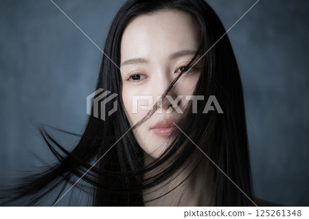 Close-up of a woman in a beauty and beauty image with her hair flying on a gray background Close-up of a woman in a beauty and beauty image with her hair flying on a gray background 125261348