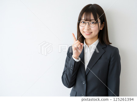 一位戴著眼鏡的微笑女士指著一個點 一位戴著眼鏡的微笑女士指著一個點 125261394