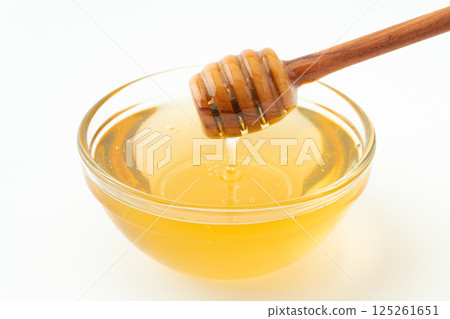Honey in a container and a honey dipper Honey in a container and a honey dipper 125261651