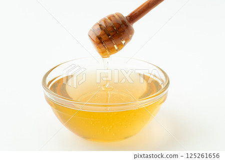 Honey in a container and a honey dipper 125261656