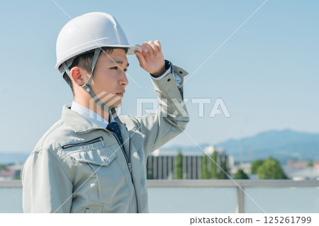 Workers wearing work clothes standing in the blue sky (construction, architecture, design, real estate, civil engineering, construction, site supervision, transportation) 125261799