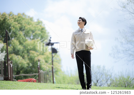 全身穿著工作服，手拿安全帽，在戶外，在新鮮的綠色植物中 施工管理、現場等的圖像 向上看 125261983