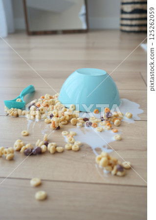 Cereal bowl spills on wooden floor creating a messy cleanup 125262059