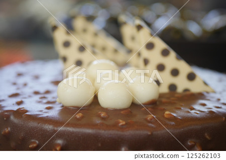 Chocolate cake decorated with cream balls and triangular pieces Chocolate cake decorated with cream balls and triangular pieces 125262103