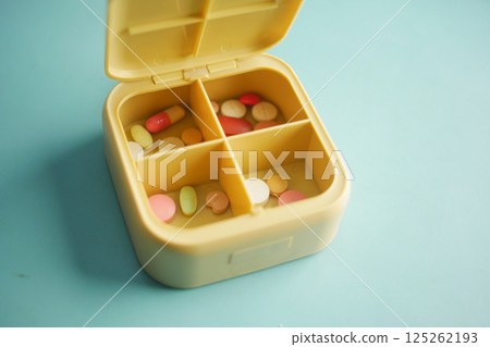 Pill organizer with various medications for daily use on blue surface Pill organizer with various medications for daily use on blue surface 125262193