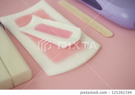 Waxing supplies arranged on a pink surface for personal care 125262194