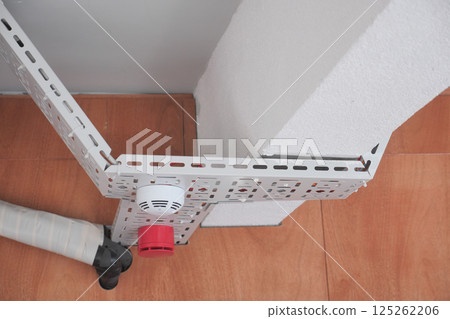 Metal brackets and a fire alarm are securely mounted in a building Metal brackets and a fire alarm are securely mounted in a building 125262206