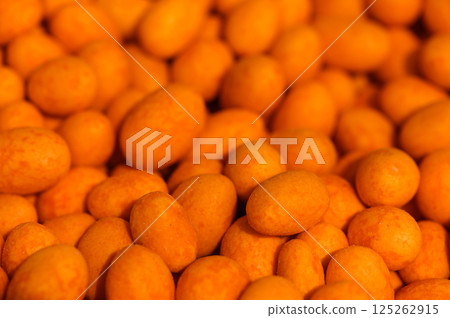 Vibrant orange candies glisten under soft light, tempting sweet lovers in a bustling market 125262915