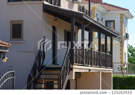 Charming residential architecture showcases balconies and staircases in a serene neighborhood during bright daylight 125262919